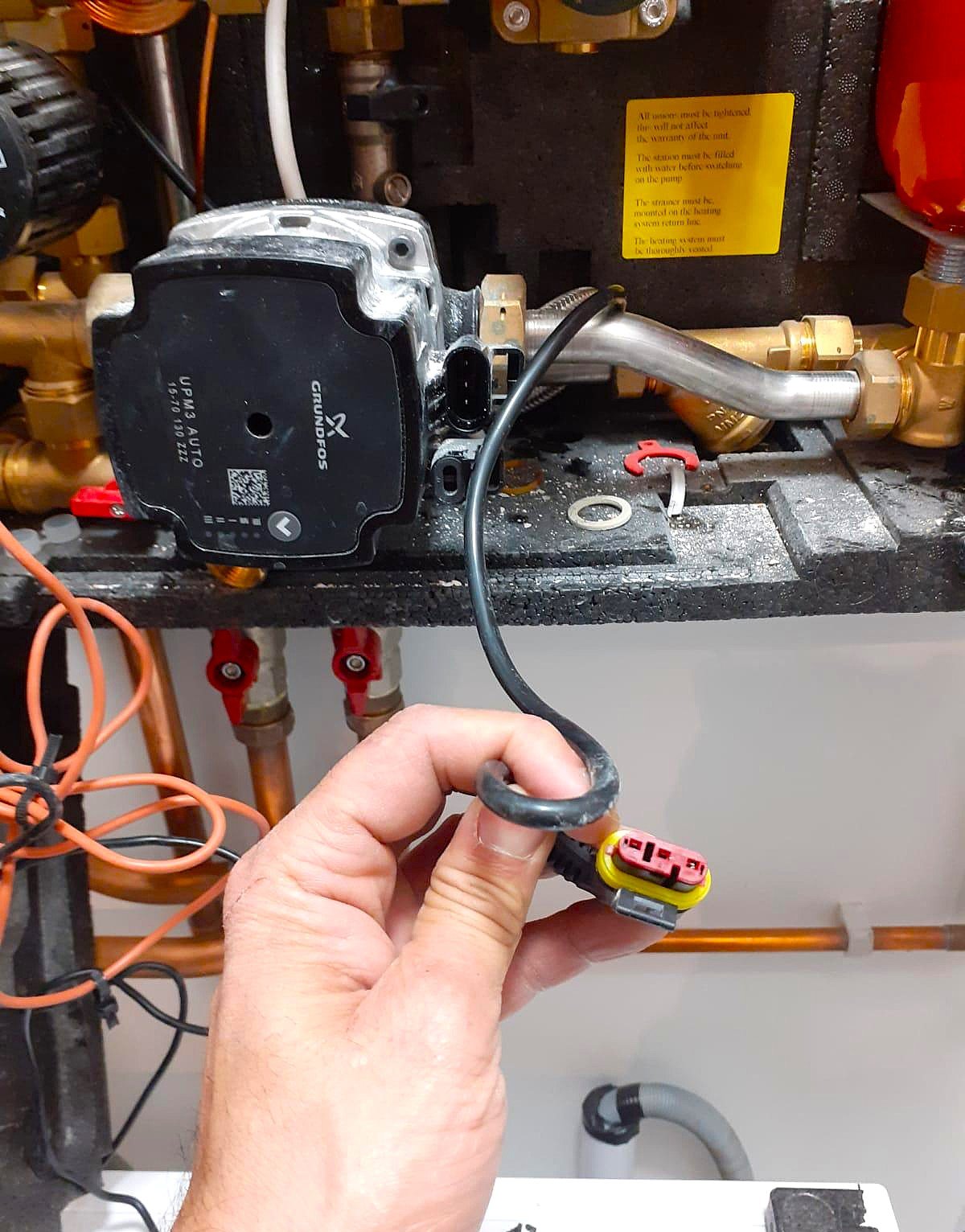 HIU engineer diagnosing electrical wiring inside Heat Interface Unit in London